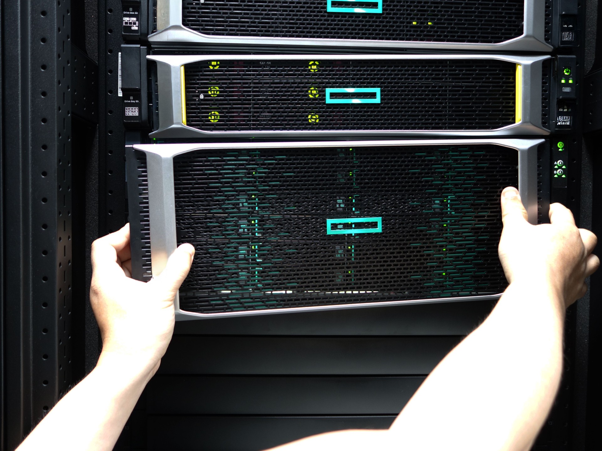 Hands Placing Server Into Rack in Data Center with Network Equipment